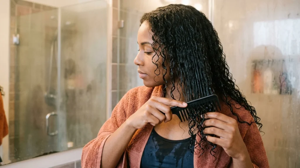Detangling wet hair gently with a wide-tooth comb to prevent breakage